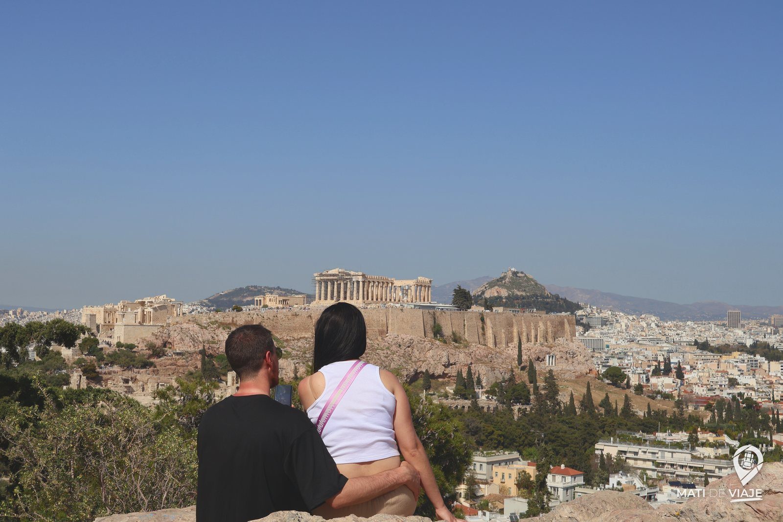 Pareja mirando la Acrópolis y el monte Licabeto desde una colina de Atenas
